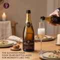 Bottle of Mueganheira sparkling wine being poured into a glass on a dining table with plates and candles.