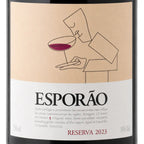 A close-up of a wine bottle label for Esporão Reserva 2023. The label has a warm beige upper section with a minimalist line drawing of a person holding a glass of red wine, and a white lower section with black and red text.