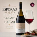A bottle of Esporão Reserva red wine stands next to a filled wine glass, with food garnishes and promotional text on a warm beige background.