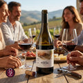 A bottle of wine with a visible PORTAL label stands on a wooden table in a vineyard setting, surrounded by people holding wine glasses and enjoying food outdoors.