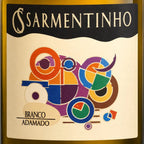 Close-up of a wine bottle label reading 'SARMENTINHO' and 'BRANCO ADAMADO', with a cream background and colorful abstract geometric artwork in orange, purple, blue, green, yellow, and brown.