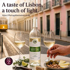 A bottle of Sotta white wine is displayed on a table with two filled wine glasses, olives, cheese, and a corkscrew in a street setting. Text at the top reads 'A taste of Lisbon, a touch of light.