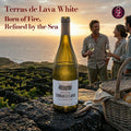 Terras de Lava White wine bottle with people enjoying a sunset at a vineyard.