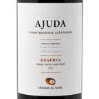 A close-up of a wine bottle label reading AJUDA Reserva Vinho Tinto Red Wine 2021, with a white label, black text, and a small gold seal on a dark bottle background.