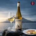 Oceánico white wine bottle with a glass and plate of food against a mountainous background