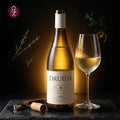 A bottle of Druida white wine with a matching wine glass, a cork, and a corkscrew on a dark stone surface against a dark background with soft botanical accents.