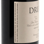 Close-up of a wine bottle label with the brand DRUIDA visible, showing part of the dark bottle and a cream-colored label with black text.