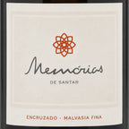 Close-up of a wine label reading 'Memórias de Santar' with an orange geometric flower logo and 'ENCRUZADO • MALVASIA FINA' at the bottom, shown against a dark bottle background.