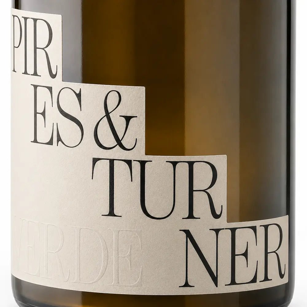 Close-up of a dark amber glass bottle with a cream-colored paper label featuring black serif text that reads 'PIRES & TURNER' .