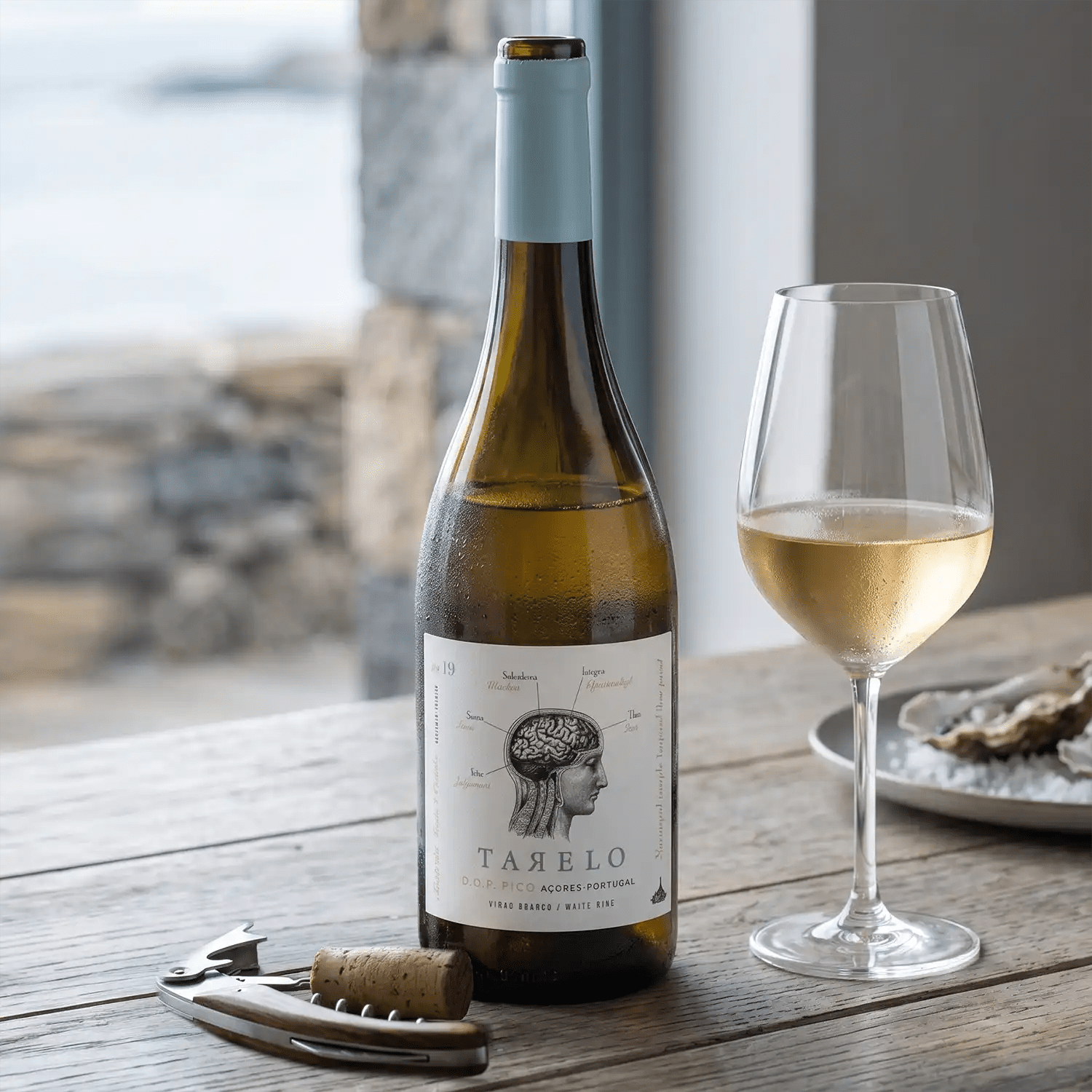 Wine bottle Tarelo with a glass of white wine on a wooden table outdoors.
