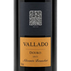 A close-up of a wine bottle label for Vallado-Alicante-Bouschet-2021, featuring a black upper section with a silver crest and a warm golden-brown lower label with black text.