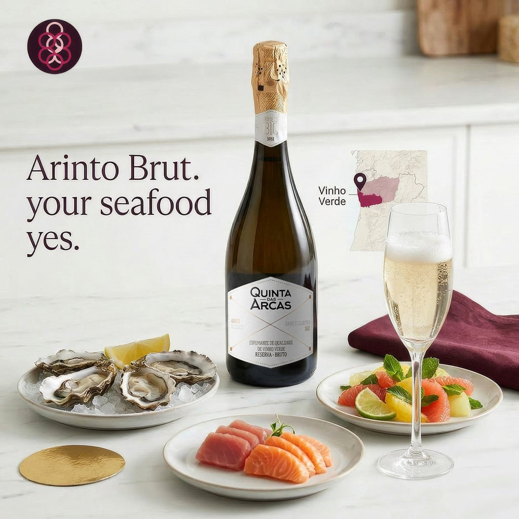 Bottle of Quinta Arcas Arinto Brut with a glass of champagne and plates of seafood on a white surface.
