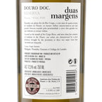 Close-up of a wine bottle label reading Duas Margens 'DOURO DOC. RESERVA' and 'duas margens', with Portuguese text, alcohol content, and a barcode on a dark bottle background.