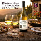 A bottle of white wine with two filled wine glasses on an outdoor dining table at sunset, with food dishes and a stone building in the background. Portuguese marketing text appears around the product.