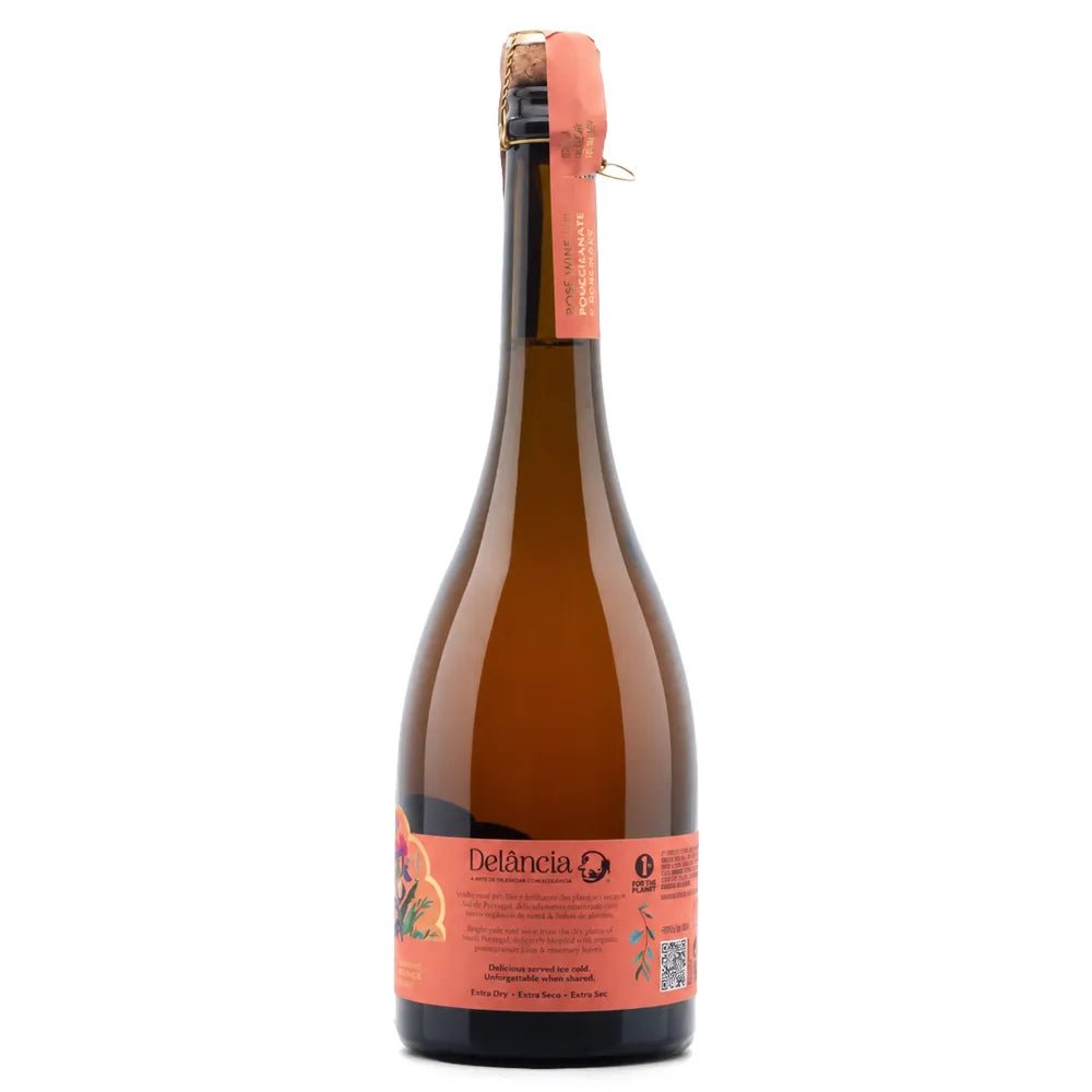 A bottle of Deláncia sparkling wine with a dark amber glass body, a coral-pink label, and a matching foil seal on a white background.