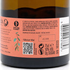 Close-up of a dark bottle label with a peach-pink background, barcode, QR code, nutritional information, and Portuguese text. The bottle itself is dark brown/black glass with a yellowish olive oil visible at the top.