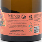 Close-up of a wine bottle label reading Delância, with a peach label on a dark brown bottle. Visible text includes product details and a QR code.
