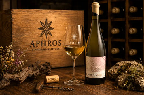 Aphros wine bottle and glass on a wooden table with a wooden crate in the background.
