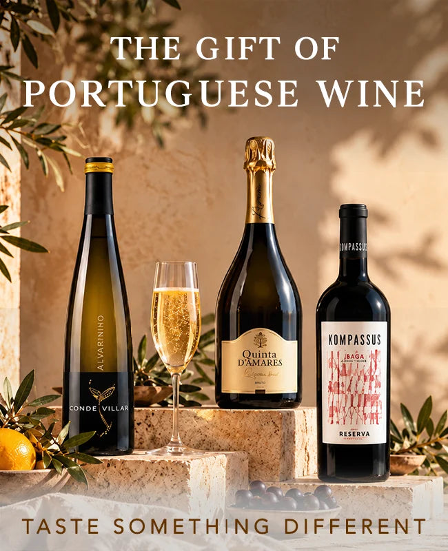 Three bottles of Portuguese wine and a filled wine glass arranged on stone blocks with decorative leaves and oranges. Large text reads 'THE GIFT OF PORTUGUESE WINE' and 'TASTE SOMETHING DIFFERENT'.