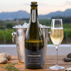 Bottle of Impossivel wine with a glass of champagne in a vineyard setting