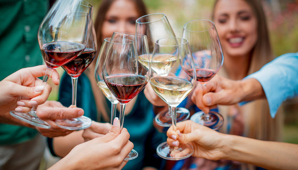 People holding wine glasses in a celebratory manner outdoors