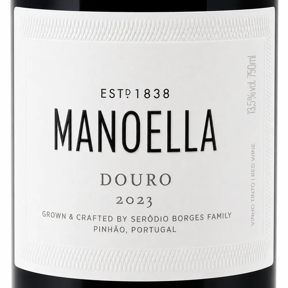 Close-up of a white wine label for Manoella Douro 2023, with black text and a dark bottle edge visible around the label.